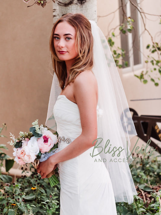 Angel cut one tier wedding veil with cut edge shown in cathedral length with a cascading silhouette