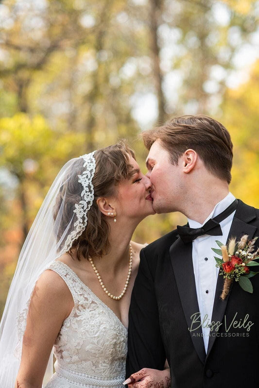 Light ivory or soft white lace mantilla wedding veil with soft drape, fingertip to cathedral length, scalloped lace edge, and timeless elegance.