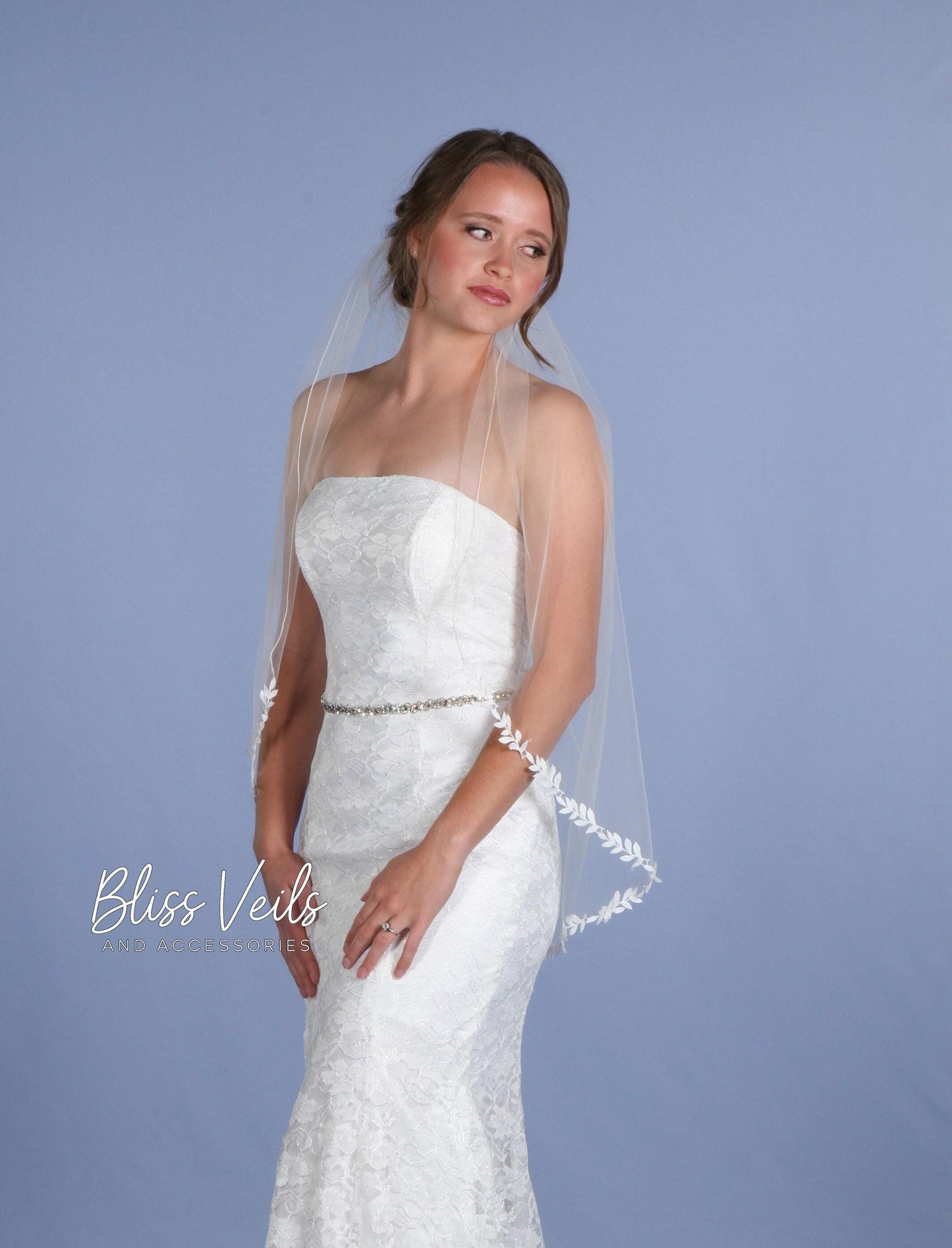 Ivory leaf design one-tier wedding veil made of soft tulle, shown in fingertip length, also available in long chapel length.