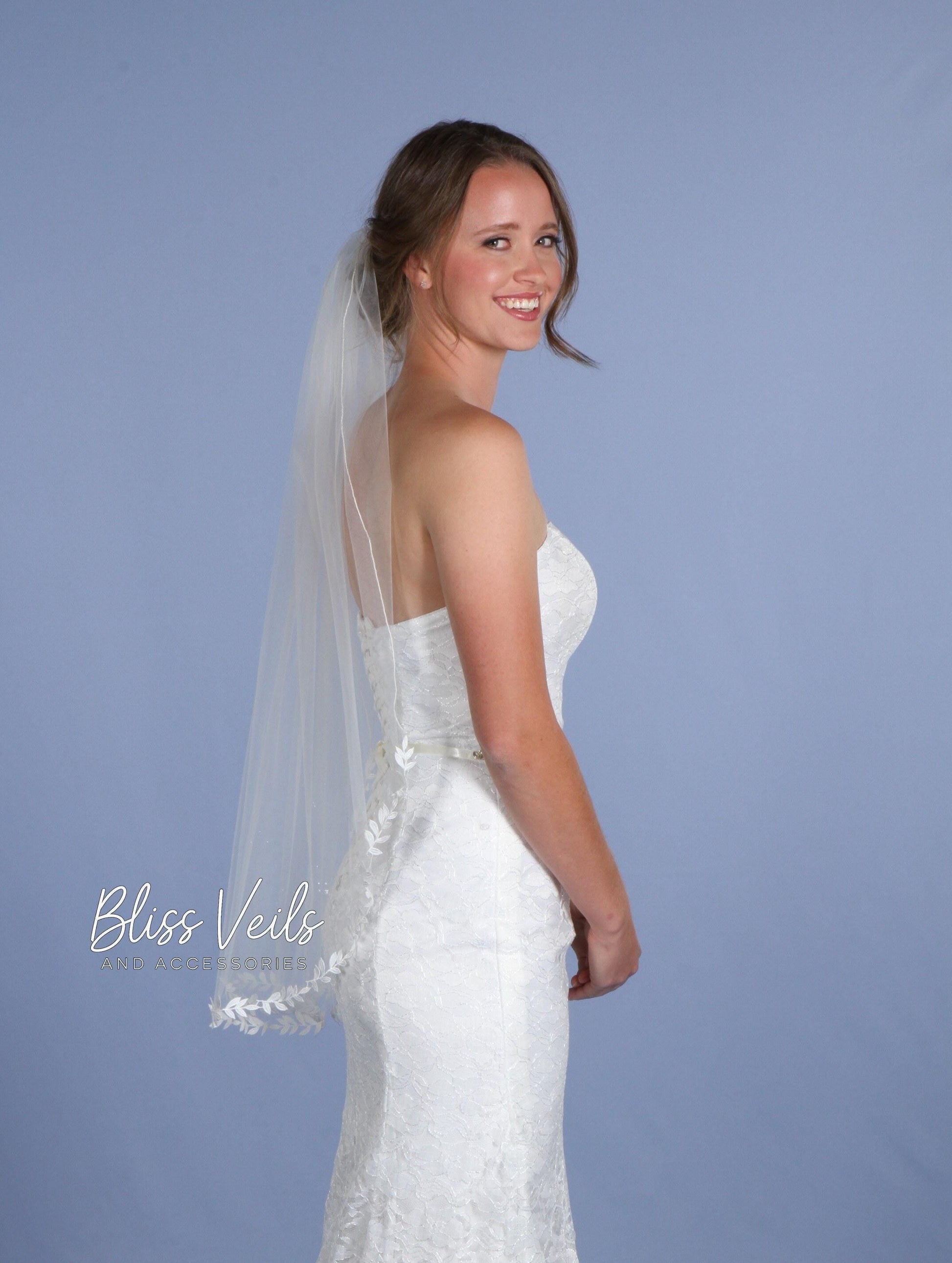 Bride wearing ivory one-tier wedding veil with delicate leaf lace trim