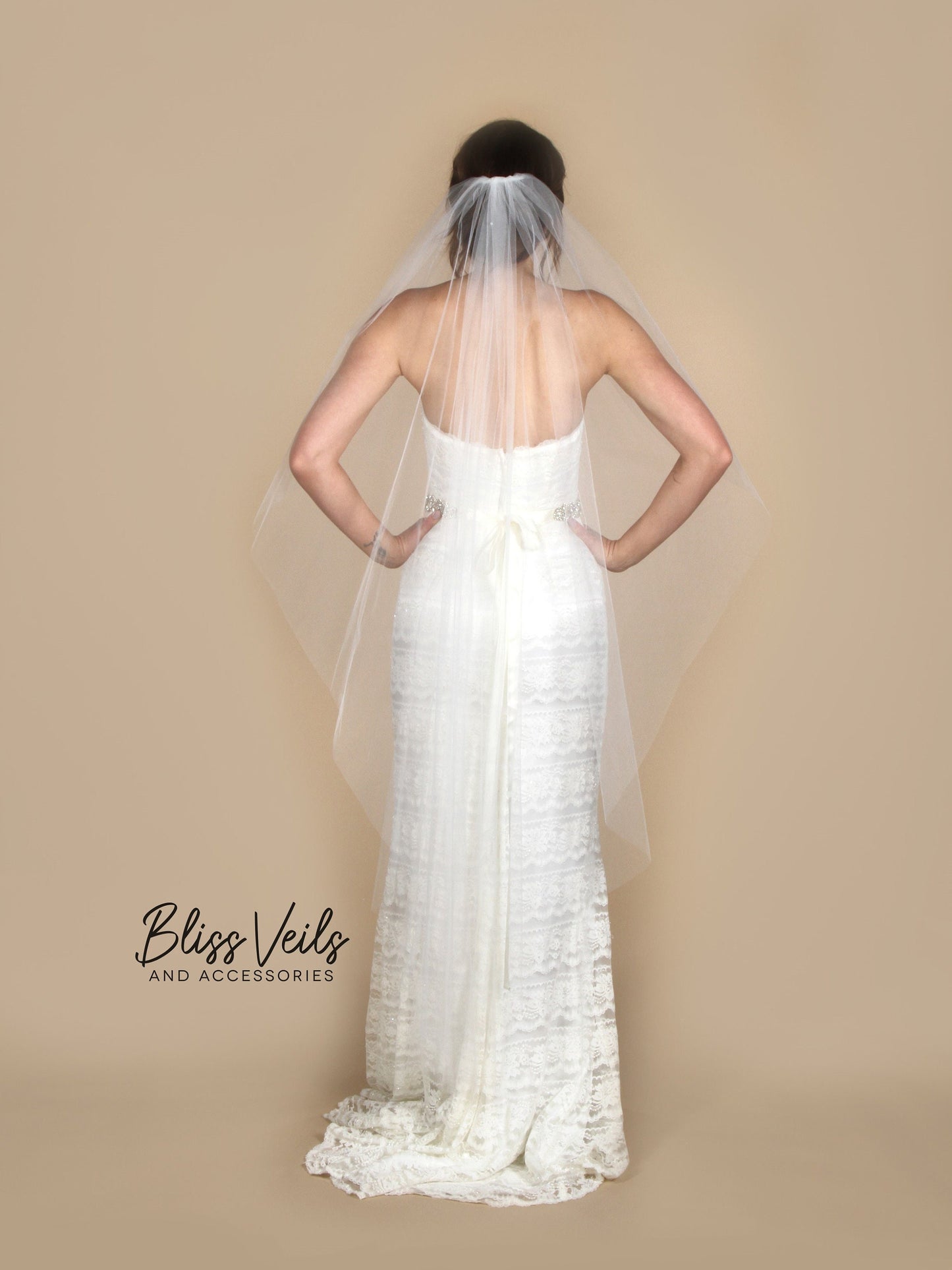 Angel cut veil that cascades down the sides to a longer back with a plain cut edge.  Available in fingertip to cathedral lengths. Made with soft bridal tulle it is sewn to a metal comb for easy attachment.